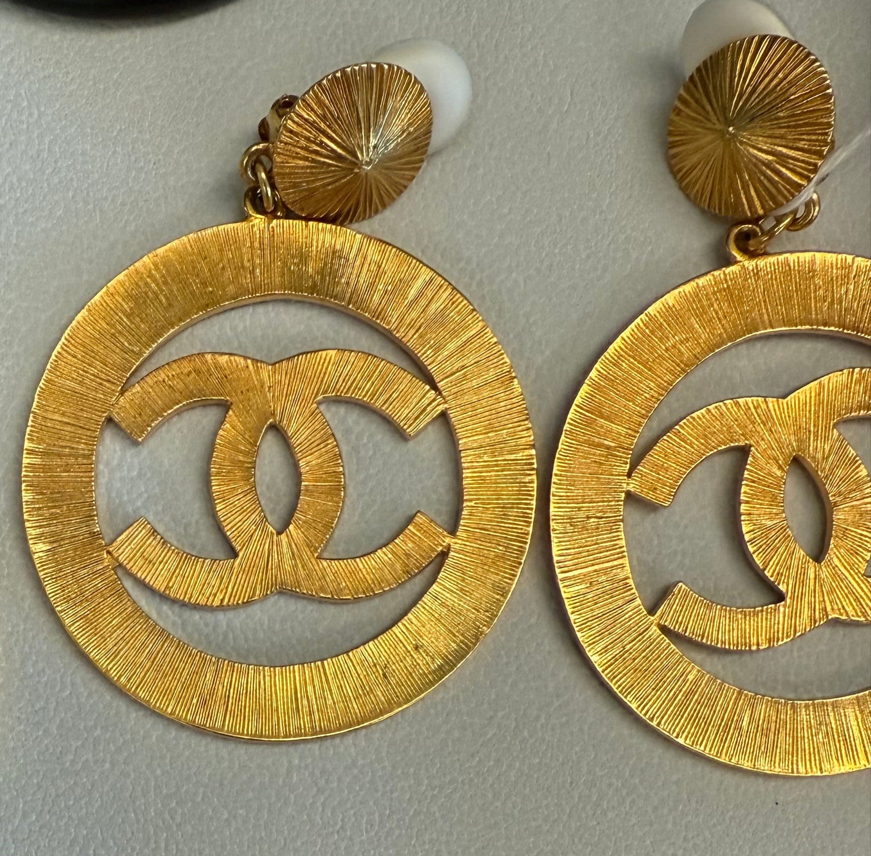 Gold Chanel earrings on a light gray background